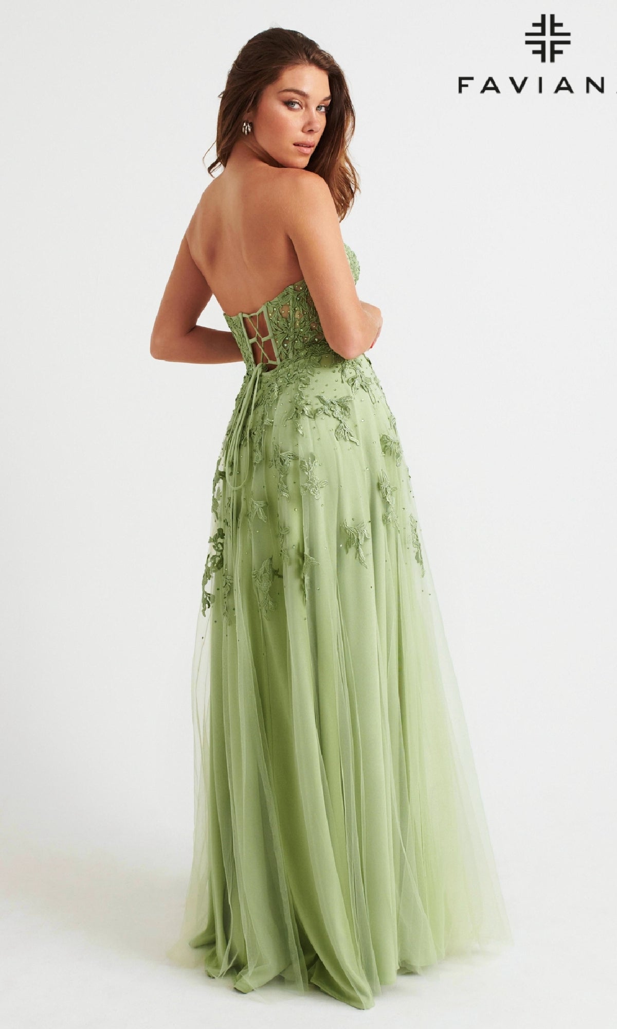 A woman wearing the Faviana Strapless Sweetheart Long Lace Prom Dress in light green with floral embroidery stands facing slightly away. The Faviana logo is displayed in the top right corner.